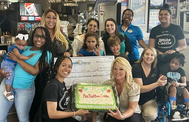 White Castle team members and families gather around a celebratory cake at a community event.